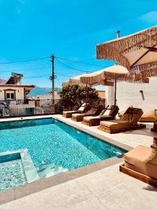 a swimming pool with lounge chairs and umbrellas at Hotel Mihasi in Ksamil