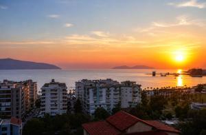 a sunset over a city with buildings and the ocean at Deon in Vlorë