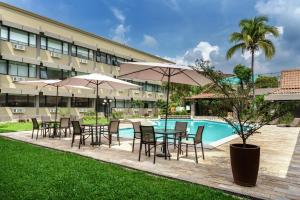 ein Tisch und Stühle mit Sonnenschirmen neben einem Pool in der Unterkunft Best Western Plus Hotel Terraza in San Salvador