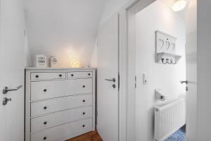 a white bedroom with a dresser and a closet at Reetdachkate in Esgrus +34 photos