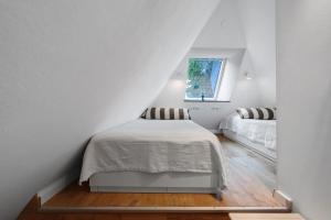 a white bedroom with a bed and a window at Reetdachkate in Esgrus