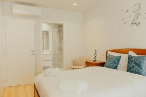a bedroom with a large white bed with blue pillows at Gerês Thermal Escape in Geres +50 photos
