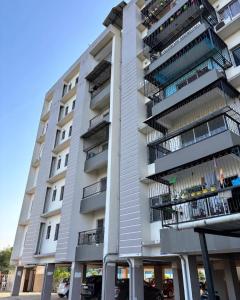 ein hohes Gebäude mit Balkonen und davor geparkten Autos in der Unterkunft Transit Nest 1BHK in Guwahati
