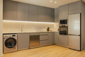 a kitchen with gray cabinets and a washer and dryer at Gerês Thermal Escape in Geres