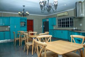 a kitchen with blue cabinets and wooden tables and chairs at Kariebi Guest House in Bethlehem