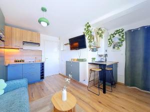 a kitchen with blue cabinets and a table in a room at Stella Plage, Studio Vert et Mer in Cucq