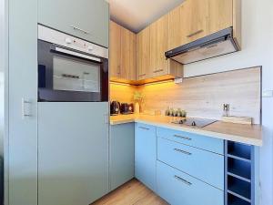 a kitchen with blue cabinets and a white refrigerator at Stella Plage, Studio Vert et Mer in Cucq +3 photos