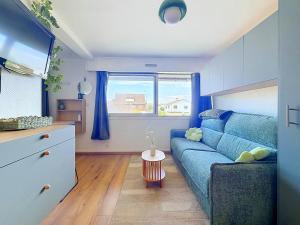 a living room with a blue couch and a window at Stella Plage, Studio Vert et Mer in Cucq