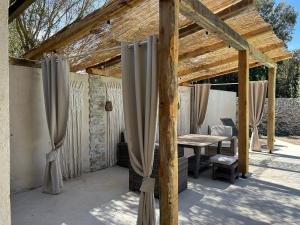 a wooden pergola with curtains and a table at Résidence Alba in Bonifacio