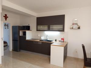a small kitchen with black cabinets and a refrigerator at Apartmani Masline Međugorje in Međugorje