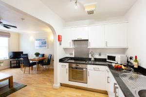 a kitchen with white cabinets and a dining room at SACO Jersey - Merlin House in Saint Helier Jersey