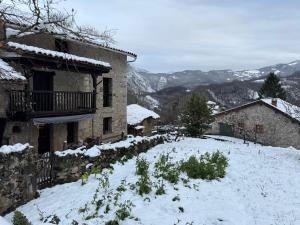 a house with snow on the ground next to a building at Casa de Aldea EL Fusu in Taranes
