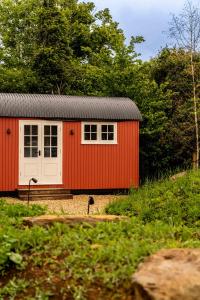 a red shed with a white door and trees at The Norman Knight in Whichford