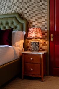 a lamp on a night stand next to a bed at The Norman Knight in Whichford