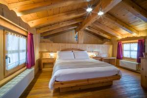 a bedroom with a large bed in a room with wooden ceilings at Hotel Garni Plueme in Sauris