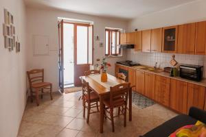a kitchen with a wooden table and chairs and a table and a kitchen at Casa Lina - 10 minuti da Pantalica-parcheggio gratuito in Sortino