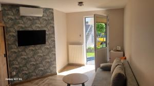 a living room with a couch and a tv on a wall at Wrzosowa 34 in Augustów