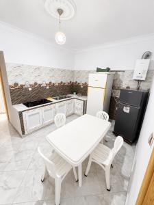 a white kitchen with a white table and chairs at Azure Coast Residence in Mostaganem