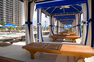 a row of picnic tables with blue umbrellas and a pool at North Beach Resort & Villas in Myrtle Beach