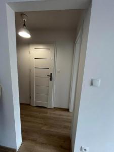 an empty hallway with a white door and wooden floors at Przystań Kamień Centrum in Kamień Pomorski
