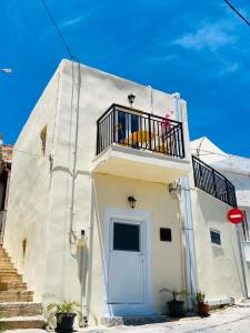 a white building with a balcony and a door at Plativola Mountain View in Sitia +2 photos