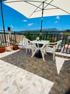 a white table and chairs on a balcony with an umbrella at Plativola Mountain View in Sitia