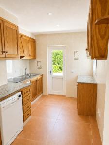 a kitchen with wooden cabinets and a white dishwasher at Villa Gabriela in S'Algar