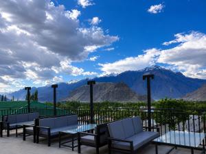 eine Gruppe von Stühlen und Tischen auf einem Balkon mit Bergen in der Unterkunft Fialong Hotel Skardu in Skardu
