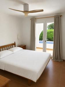 a bedroom with a white bed with a ceiling fan at Villa Gabriela in S'Algar +8 photos