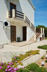 a white house with a staircase and flowers at ThePAGHouse in Pag