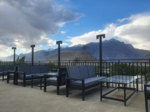 eine Gruppe von Stühlen und Tischen auf einem Balkon mit Bergen in der Unterkunft Fialong Hotel Skardu in Skardu
