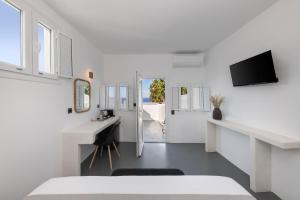 a white room with a white desk and a tv at Elios Cave Suites in Oia