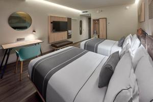 a hotel room with two beds and a television at City Express Plus by Marriott Merida in Mérida