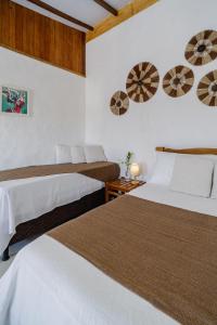 two beds in a room with white walls at Pousada Kiarô Caraíva in Caraíva
