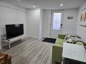 a living room with a television and a green couch at Private Entry-Modern & Bright Longueuil Suite in Longueuil