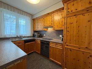 a kitchen with wooden cabinets and a black dishwasher at Viktoria B19 by Arosa Holiday in Arosa +11 photos