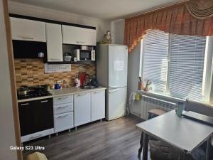 a kitchen with white cabinets and a white refrigerator at Zatishok Guest House in Rakhiv +9 photos