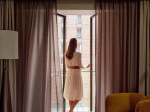 a woman in a white dress looking out of a window at Sofitel Sydney Wentworth in Sydney