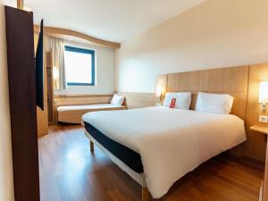 a hotel room with a large white bed and a couch at Ibis Ripollet in Ripollet