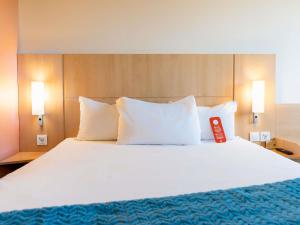 a large white bed with a red remote control on it at Ibis Ripollet in Ripollet +132 photos
