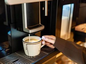 a person is making a cup of coffee in a microwave at Ibis Ripollet in Ripollet