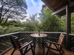a table and chairs on a deck with a bottle of wine at Grand Mercure Puka Park Resort in Pauanui +84 photos