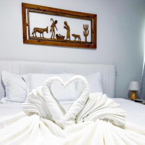 a heart shaped towel on a bed with a picture on the wall at Hotel Glória in Piranhas