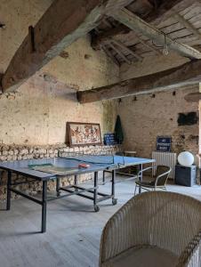 a ping pong table in a room with two chairs at Maison Flora Saint Jean d'Angely in Vervant