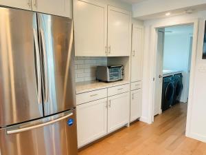 a kitchen with white cabinets and a stainless steel refrigerator at Endless Summer Oceanside Views in Boston