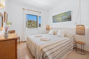 a white bedroom with a bed and a window at Tramontana 113 P1 by 3VILLAS in Fornells +17 photos