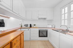 a white kitchen with white cabinets and a sink at Tramontana 113 P1 by 3VILLAS in Fornells