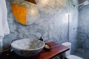 a bathroom with a large stone sink on a wooden table at Pousada Kiarô Caraíva in Caraíva