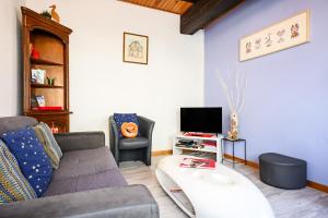 a living room with a couch and a tv at Gîte Le Nain Rouge in Kaysersberg