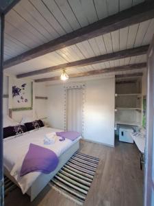 a bedroom with a large bed with purple pillows at Căsuța Veselă in Tătuleşti